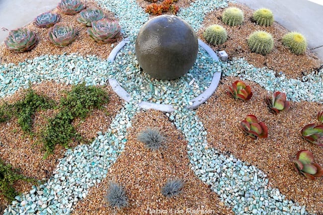 Blue stones suggest flowing water in circular succulent garden 