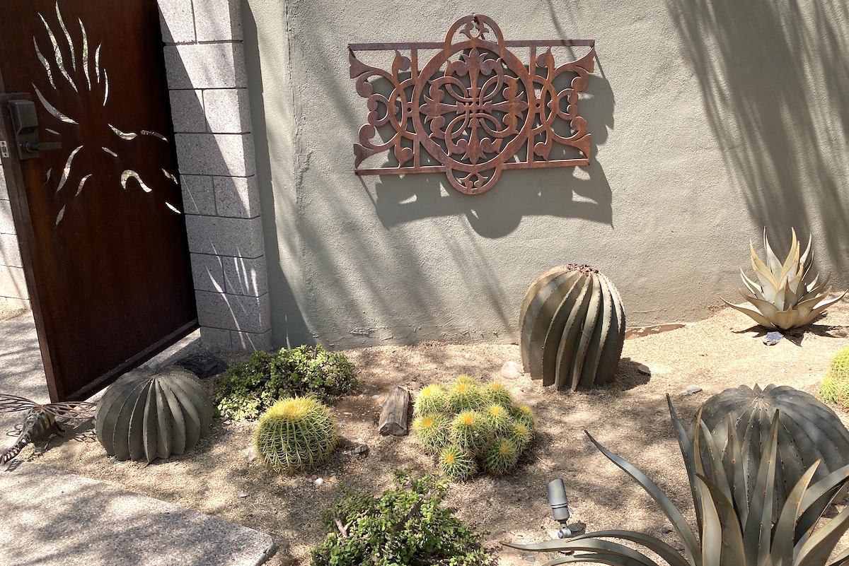 Janet Orr's desert garden with metal gate, wall art, cacti, agaves